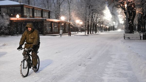 Человек едет на велосипеде во время снегопада в Москве. Архивное фото