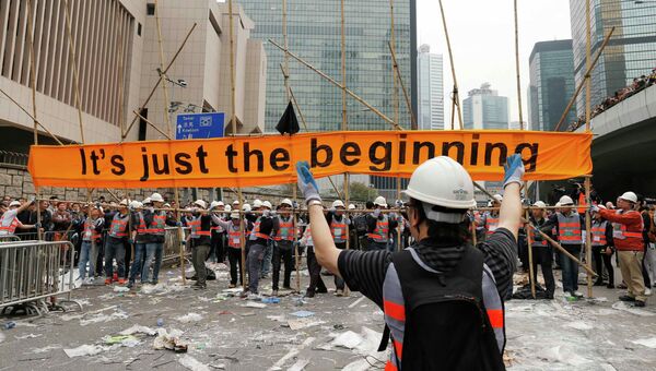 Рабочие демонтируют баннер, установленный протестующими в Гонконге