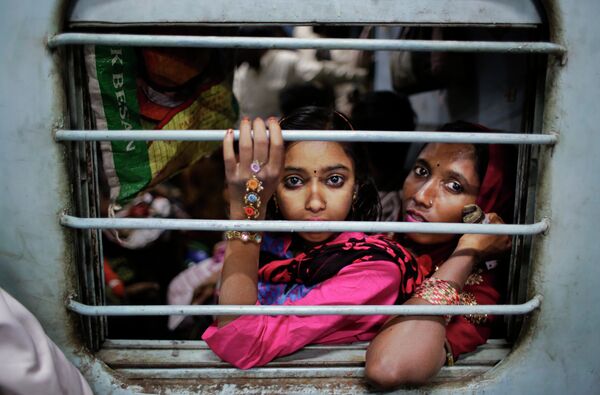 Девочка сидит на коленях у своей матери в поезде на железнодорожной станции в Нью-Дели