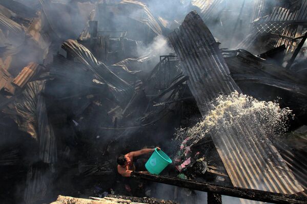Доброволец помогает тушить пожар в трущобах Манилы