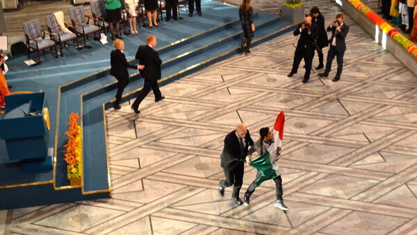 Сотрудник службы безопасности уводит молодого человека с мексиканским флагом во время церемонии награждения Нобелевской премии мира. Осло, 10 декабря 2014 год