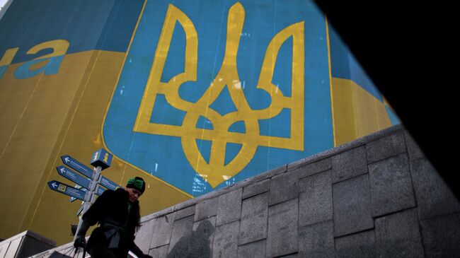 Женщина проходит мимо огромного украинского флага в центре Киева