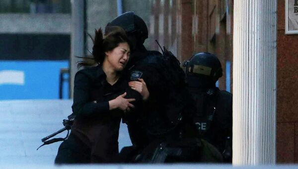 Женщина выбегает из кафе, где неизвестный держит заложников. Сидней, 15 декабря 2014