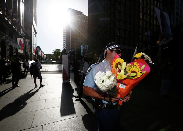 Полицейский несет цветы в память о погибших в кафе в Сиднее, Австралия