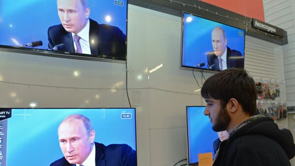 Мужчина смотрит телетрансляцию большой пресс-конференции президента России Владимира Путина в торговом центре города Грозного