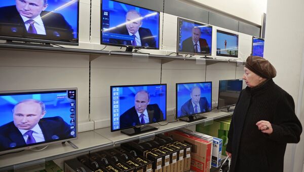 Посетительница магазина электроники в Москве смотрит телетрансляцию большой пресс-конференции президента России Владимира Путина