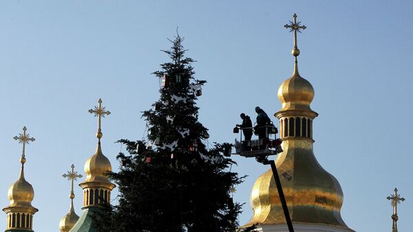 Работники украшают новогоднюю елку перед Софийским собором в центре Киева,