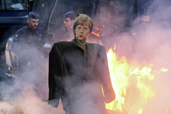 Фигура с портретом Ангелы Меркель на фоне горящих тюков соломы на акции протеста фермеров в Брюсселе