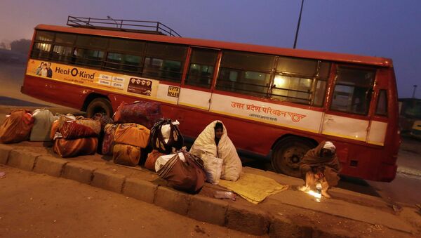 Индус завернутый в одеяло ждут их автобус на терминале на холодным зимним утром в Нью-Дели