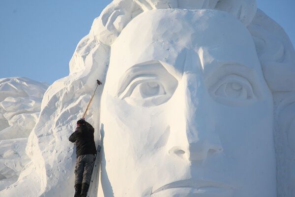 Китайский художник заканчивает работу над снежной скульптурой перед началом фестиваля в Харбине