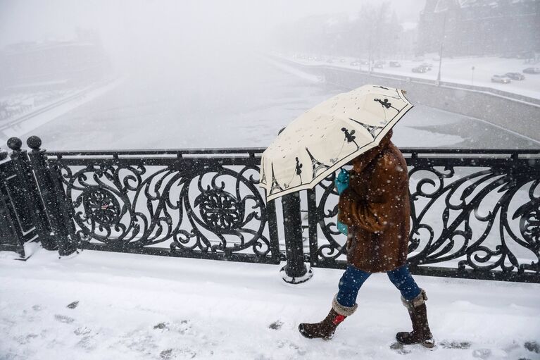 Прохожая на Патриаршем мосту в Москве во время снегопада