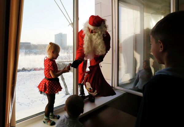 Сотрудник МЧС России Алексей Трифонов в костюме Деда Мороза дарит подарки детям