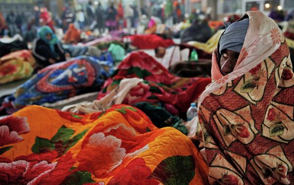 Пассажир на вокзале кутается в одеяло во время холодной погоды в Индии