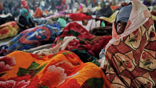 Пассажир на вокзале кутается в одеяло во время холодной погоды в Индии. Архивное фото