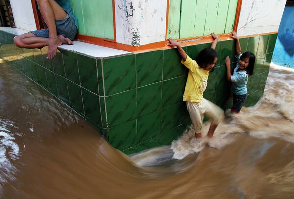 Дети на затопленной улице города Джакарта, Индонезия. 23 декабря 2014