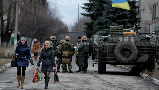 Местные жители проходят мимо солдат украинской армии в селе Дебальцево, Донецкая область. Архивное фото