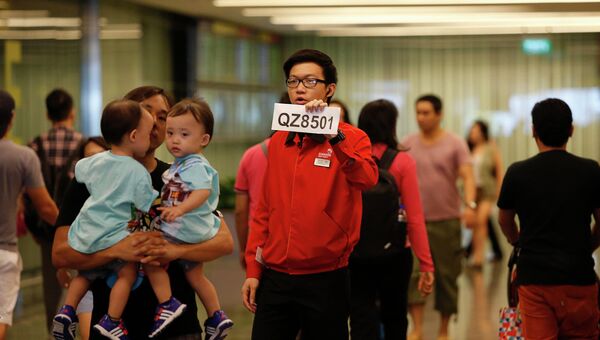 Сотрудник аэропорта Чанги держит табличку с номером пропавшего рейса QZ8501 компании Air Asia