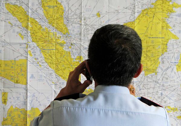 Сотрудник аэропорта смотрит на карту Индонезии в кризисном центре, созданном для поиска пропавшего рейса QZ8501 компании Air Asia