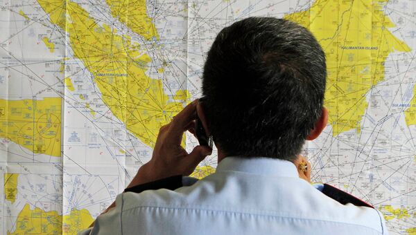 Сотрудник аэропорта смотрит на карту Индонезии в кризисном центре, созданном для поиска пропавшего рейса QZ8501 компании Air Asia
