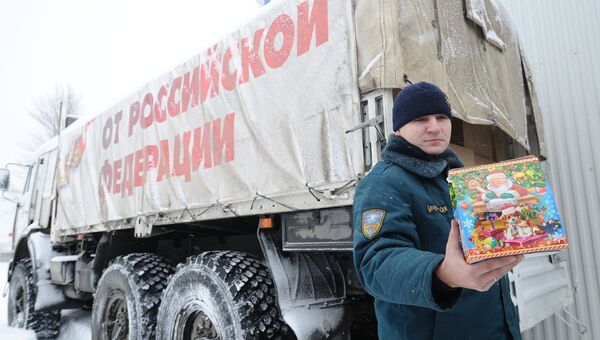 Сотрудник МЧС демонстрирует детский рождественский подарок во время формирования одиннадцатого гуманитарного конвоя для Донбасса