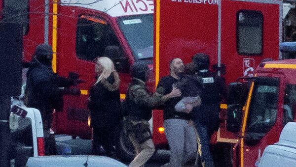 Сотрудник службы безопасности направляет освобожденных заложников после того как они ворвались кошерный рыно