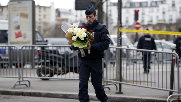 Полицейский несет цветы к месту нападения на кошерный магазин в Париже. Архивное фото