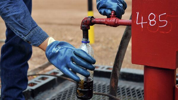 Инженер берет образец нефти на одной из скважин