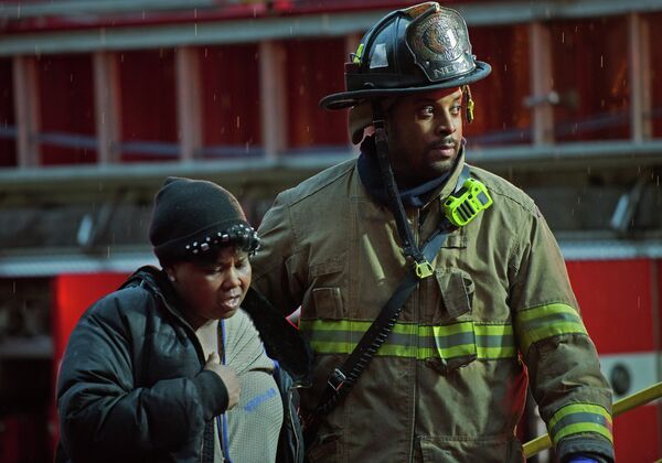 Пожарный помогает женщине, пострадавшей при задымлении на станции метро Ленфан плаза в Вашингтоне