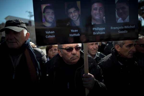 Мужчина держит плакат с портретами четырех жертв теракта в Париже