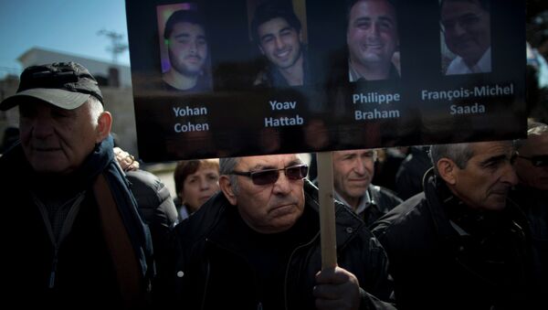 Мужчина держит плакат с портретами четырех жертв теракта в Париже