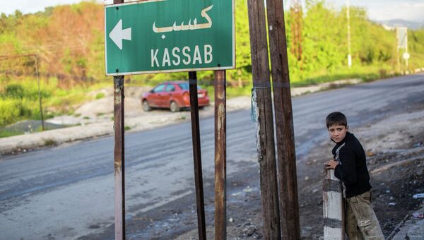Ребенок у дорожного указателя на город Кесаб на границе Сирии с Турцией. Архивное фото