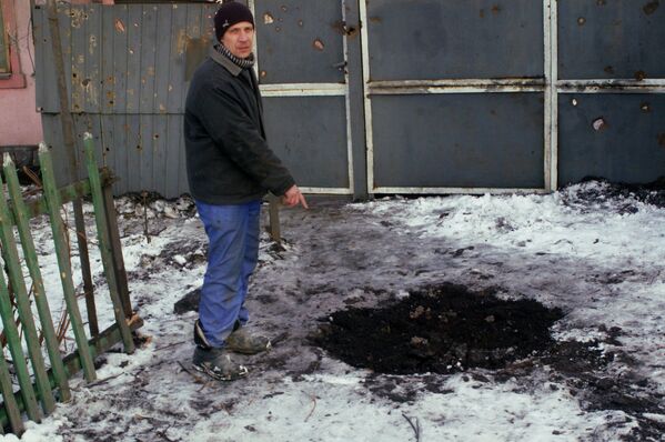 Житель Донецка показывает воронку от снаряда у дома в Червоногвардейском районе
