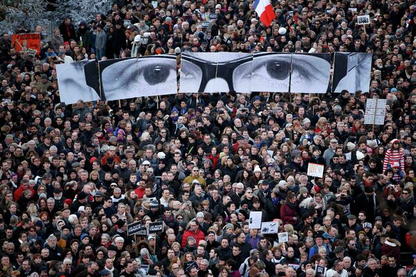 Митингующие держат панели с фотографиями глаз погибшего редактора журнала Шарли Эбдо Стефана Шарбонье
