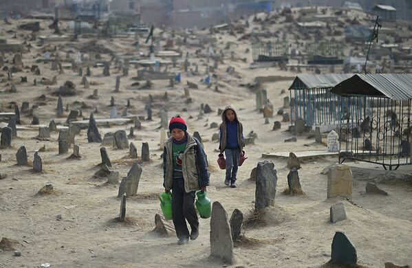 Афганские дети работают разносчиками воды на кладбище в Кабуле