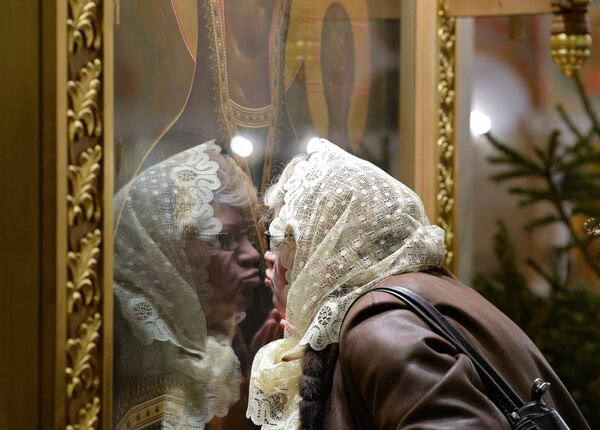 Прихожанка целует икону в кафедральном соборном храме Христа Спасителя