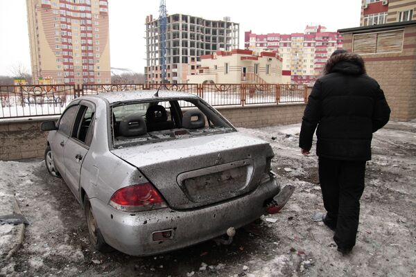 Мужчина рядом с поврежденным автомобилем после артобстрела Донецка