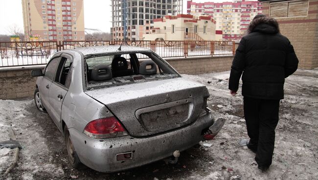 Мужчина рядом с поврежденным автомобилем после артобстрела Донецка. 18 января 2015