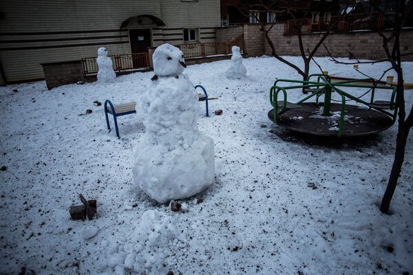 Снеговик на детской площадке, усыпанной осколками артиллерийских снарядов, после обстрела Донецка