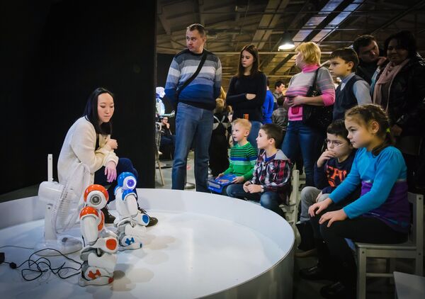 Посетители смотрят на роботов Нао на интерактивной выставке Бал роботов