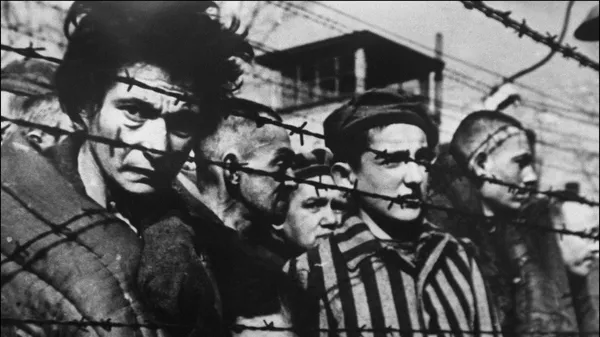 Prisoners behind barbed wire at the Auschwitz concentration camp