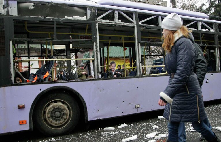 Девушка проходит мимо обстрелянного троллейбуса в Донецке