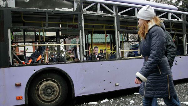 Девушка проходит мимо обстрелянного троллейбуса в Донецке
