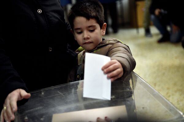 Мальчик бросает бюллетень на избирательном участке в Афинах в ходе досрочных выборов депутатов парламента Греции, 25 января 2015 года