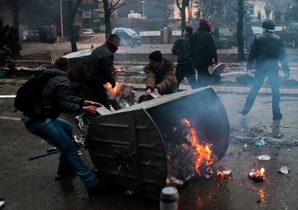 Протестующие поджигают мусорный бак во время столкновений с полицией в Приштине, Косово. 27 января 2015 год