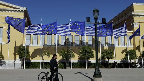 Мужчина с велосипедом на фоне флагов Греции и Евросоюза. Архивное фото