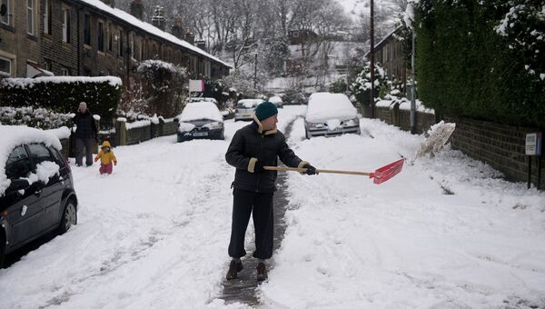 Человек очищает улицу от снега в деревне Марсден