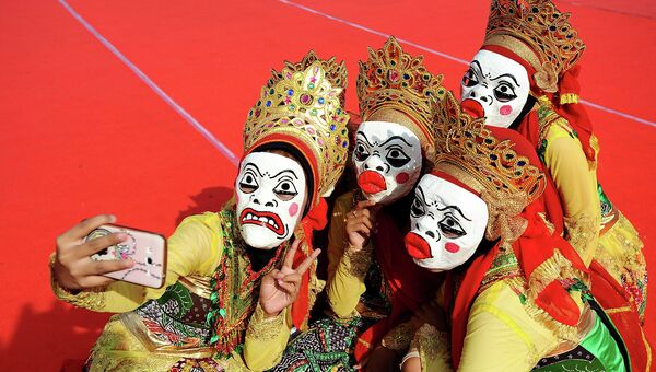 Индонезийские девушки в масках делают селфи во время ежегодного фестиваля Маулид. Индонезия