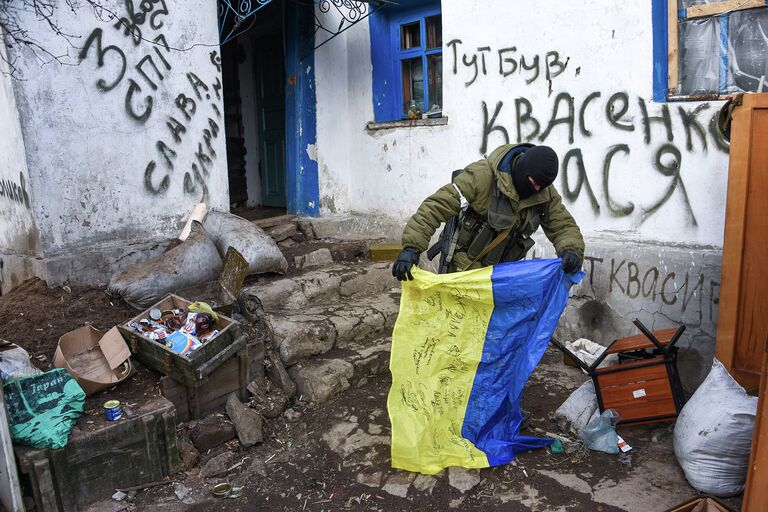 Ополченец держит флаг Украины, найденный на КПП. Восточная Украина. 24 января 2015