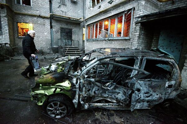 Сгоревшая автомашина у пострадавшего от обстрела жилого многоэтажного дома в Киевском районе города Донецка