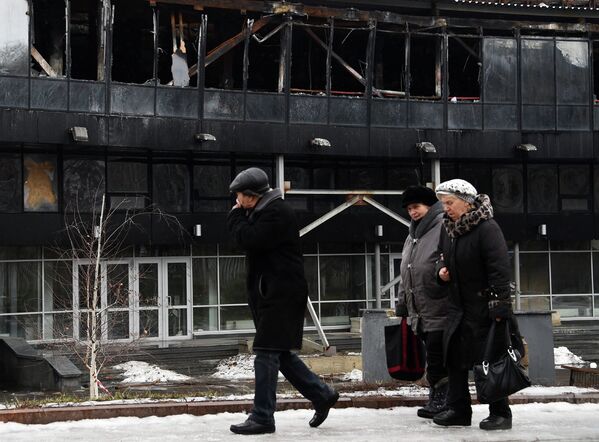 Жители Донецка на фоне поврежденного в результате обстрела здания